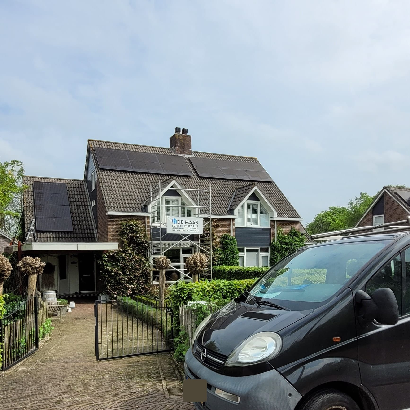 Woning met zonnepanelen, steiger met banner en de bus voor de deur