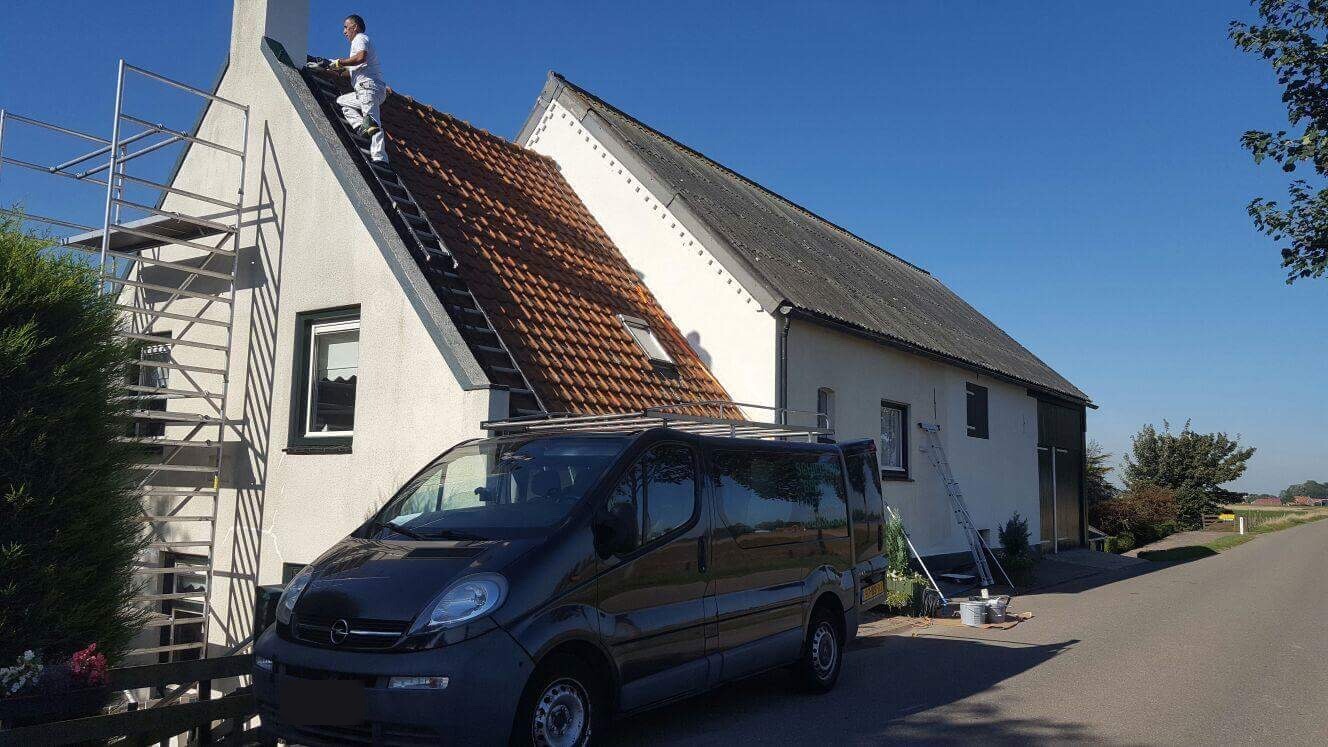 Steiger aan een witte boerderij, een schilder op het dak en de bus ernaast